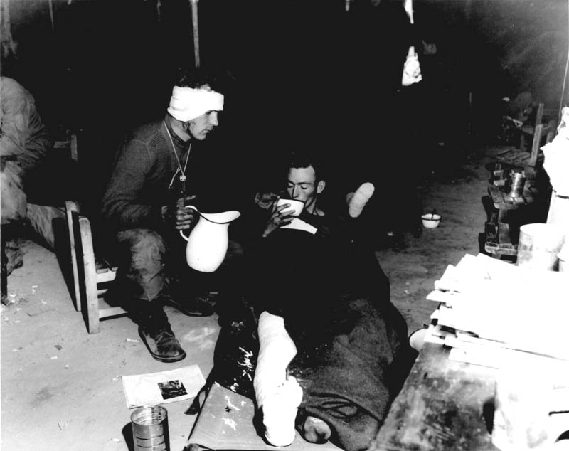 Sfc. Louis F. Walz (left), a member of Co. E, 5th Cavalry Regiment, 1st Cavalry Division, and Pfc. Raymond M. Szukla, a member of Co. G, 5th Regimental Combat Team, 24th Infantry Division, receive medical aid at the 8063rd Mobile Army Surgical Hospital, attached to I Corps in Korea. Sfc. Walz is recovering from a head wound, and Pfc. Szukla suffered a wound in the right leg while engaged in action against the Communist-led North Korean forces. 4 November 1950. Korea. Signal Corps Photo #8A/FEC-50-21377 (McIntosh).” Photo U.S. Army